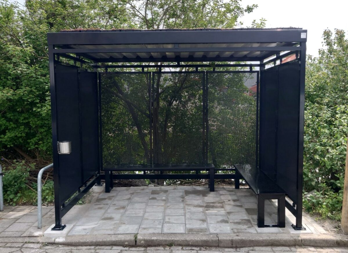 Wat kost een rookoverkapping? Prijzen en mogelijkheden in 2026 2 Moderne rookabri 3 x 2 meter met zitbank en groen dak geplaatst door SKWshop in Naaldwijk op betonnen poeren 30x30 cm